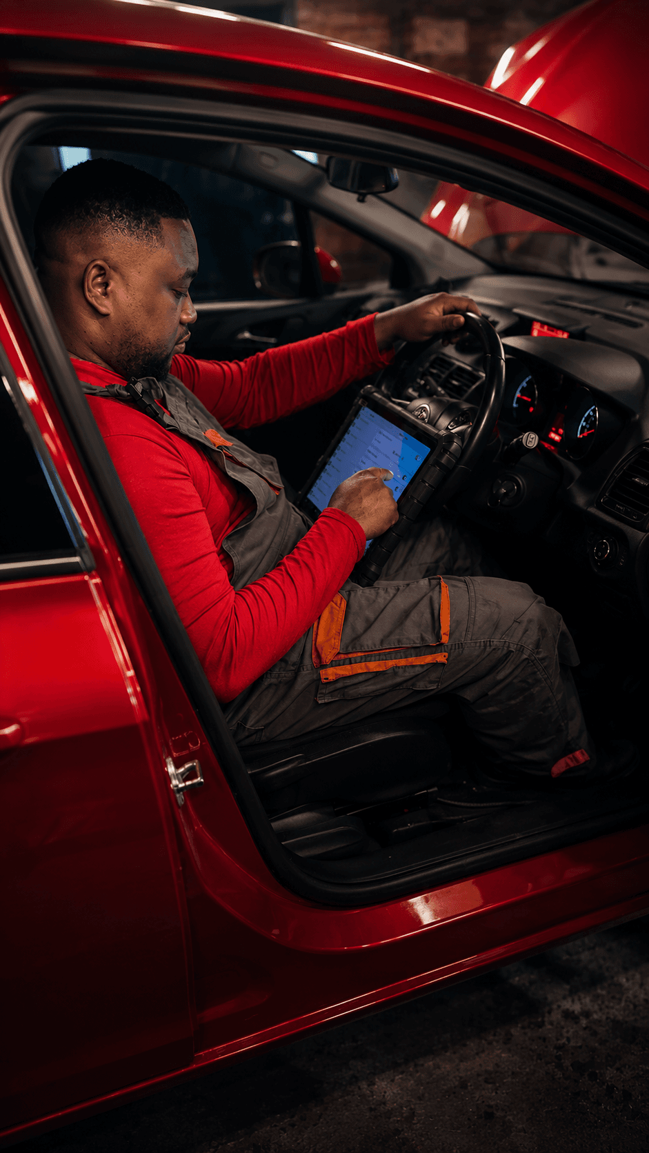 A technician using a diagnostic tablet inside a car